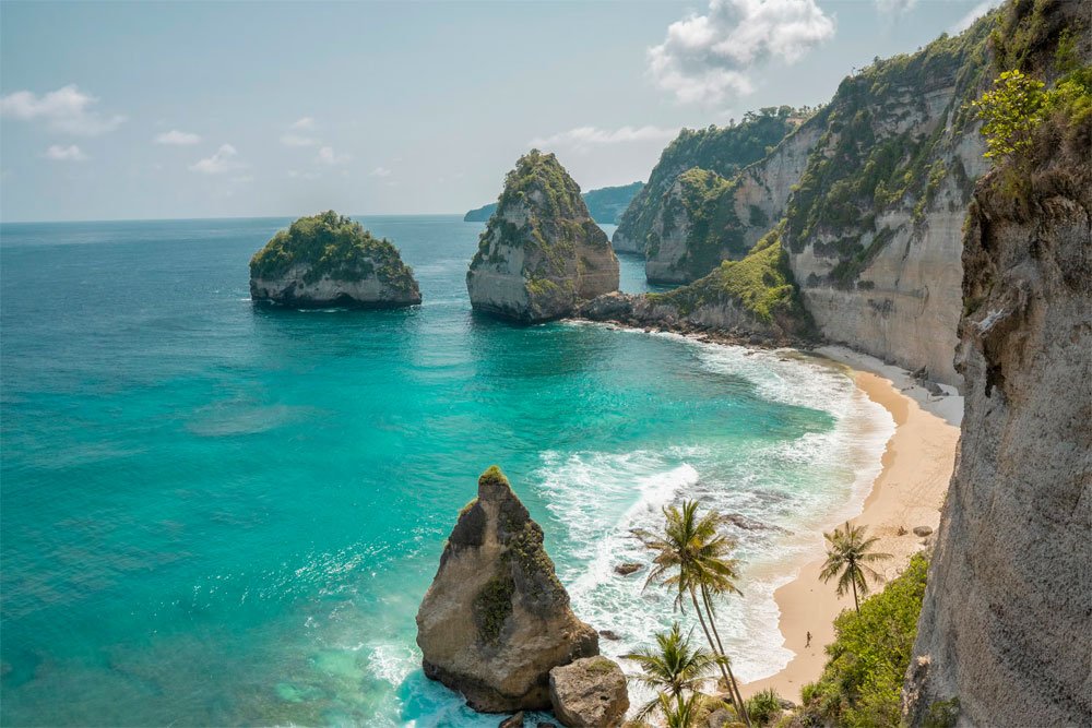 Book cheap flight to Bali beach with cliffs and turquoise ocean Indonesia